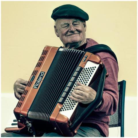 Senior man enjoying music, playing accordion with