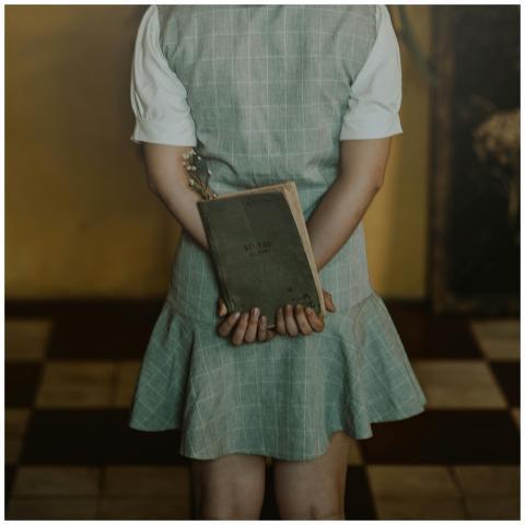 A young woman holding a book behind her back in a