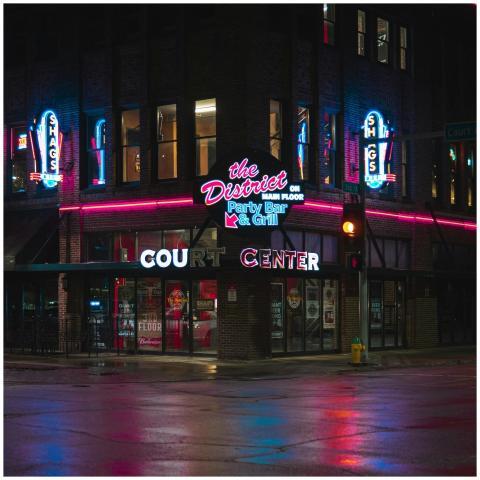 Vibrant neon lights illuminate a bar exterior in D