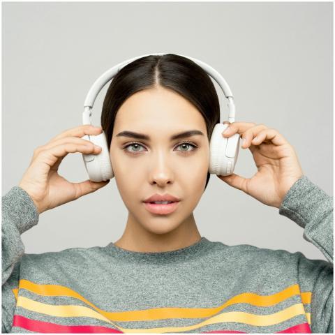 Stylish woman wearing wireless headphones, enjoyin