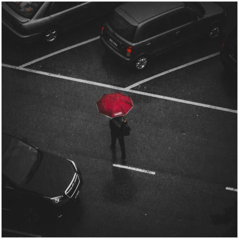 Top view of a person with a red umbrella walking i