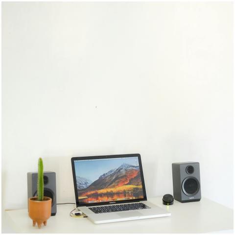 A minimalist desk setup featuring a laptop, speake