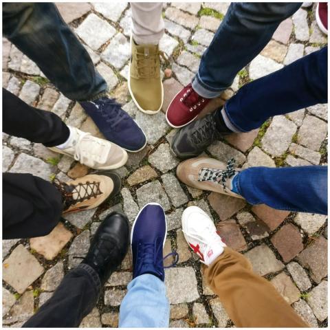Circle of sneakers on cobblestone pavement represe