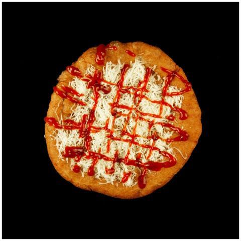 Appetizing Hungarian lángos topped with shredded c