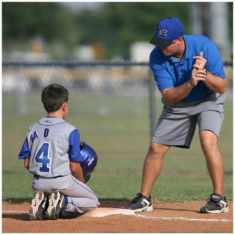 A young baseball player receives guidance from a c