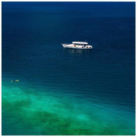 A serene aerial view of a yacht and snorkeler in t