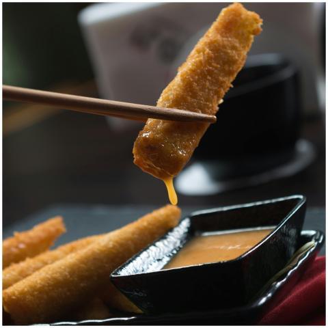 Close-up of crispy sticks being dipped in sauce wi