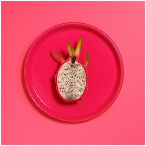 A single dragon fruit slice on a bright pink plate