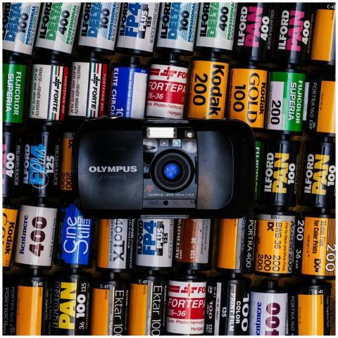 A vintage Olympus camera surrounded by colorful fi