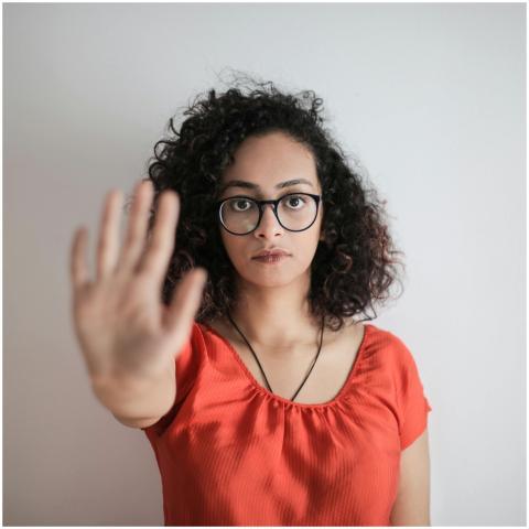 A serious woman with curly hair and glasses making