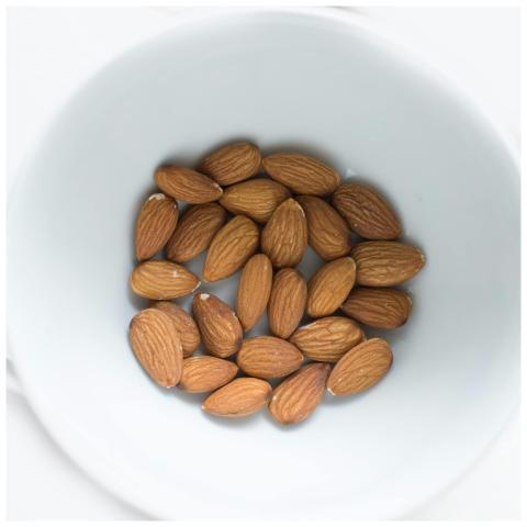 A close-up view of organic almonds in a white bowl