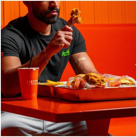 A man savoring fried chicken and fries in a bright