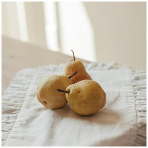 Three ripe pears placed on a cloth under warm sunl