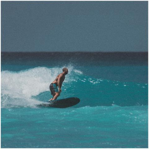 A man skillfully surfing on the vibrant waves of H