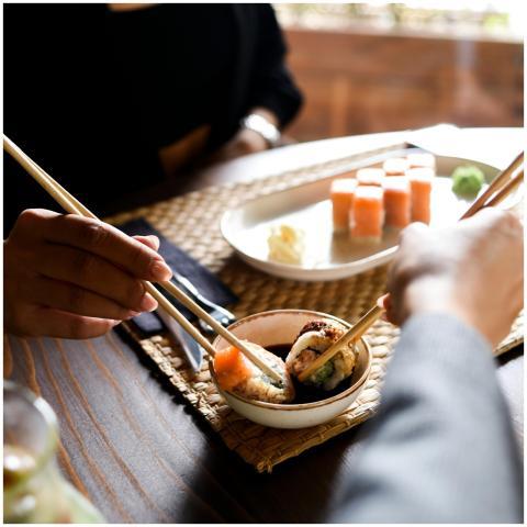 Two people sharing sushi using chopsticks, highlig
