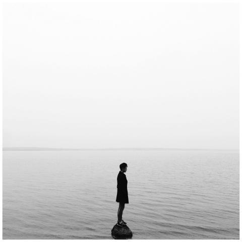Black and white image of a solitary person on a ro