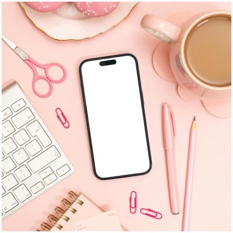 Modern pink-themed desk setup with smartphone, key