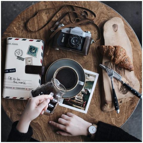 Flat lay of vintage camera, coffee cup, croissant,