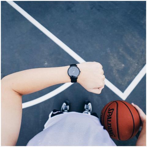A basketball player checks their wristwatch while