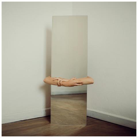 A minimalist image of a mirror reflecting a woman'