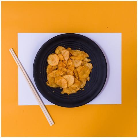 Flat lay of crunchy potato chips on a black plate