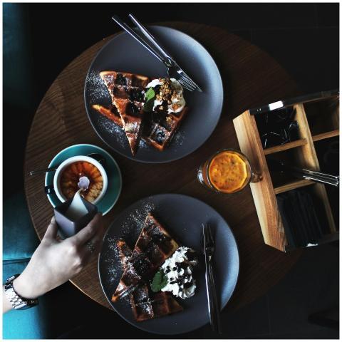 Top view of waffles, cappuccino, and juice on a wo