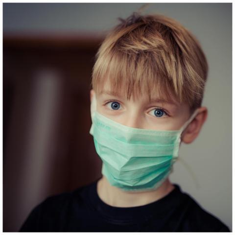 Young boy with bright eyes wearing a protective ma