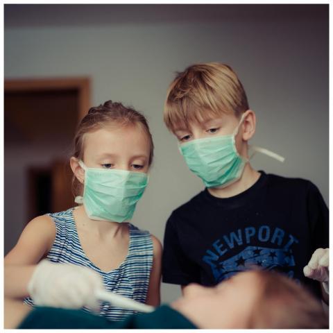 Kids playing as doctors, wearing masks and gloves