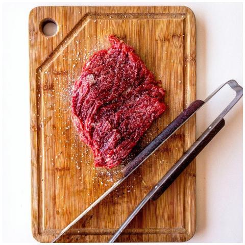Top view of seasoned raw beef steak on wooden boar