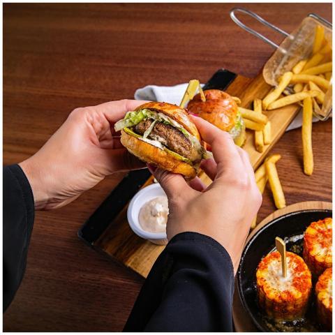 Close-up of a gourmet burger with fries on a woode