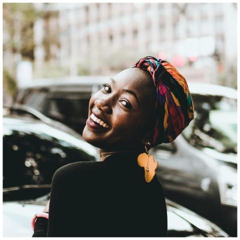 A joyful woman wearing a colorful headwrap and dis