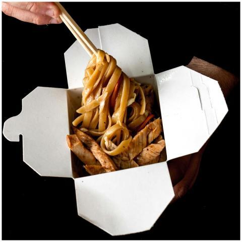 Close-up of hands holding a takeout box of spicy A