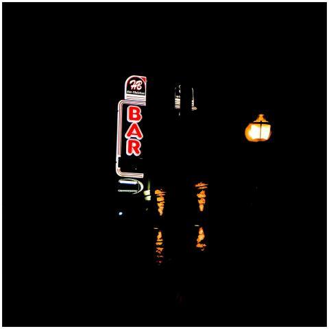 Illuminated neon bar sign with a streetlight in a