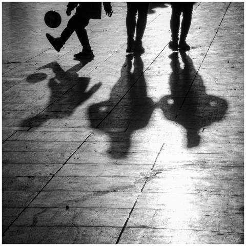 Black and white photo of silhouettes playing socce