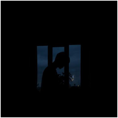 Moody silhouette of a person framed by a window wi