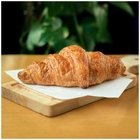 Golden-brown croissant placed on a wooden board in