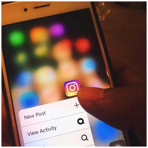 Finger navigating Instagram app on a smartphone sc
