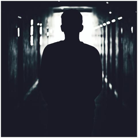 Silhouette of a person standing in a shadowy tunne