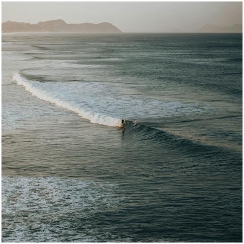 A breathtaking aerial shot of a surfer riding wave