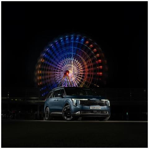 A car parked at a funfair with a vibrant neon-lit