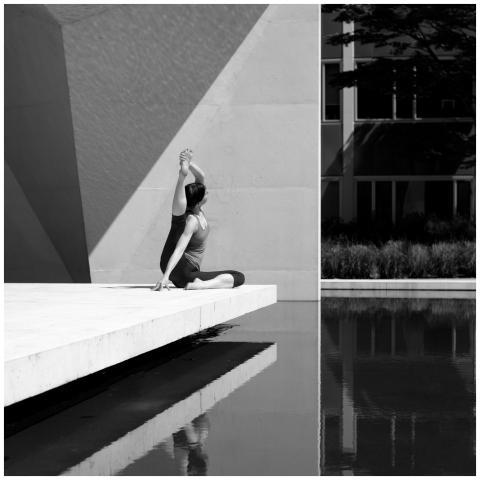 A woman practicing yoga by a reflective pool, show