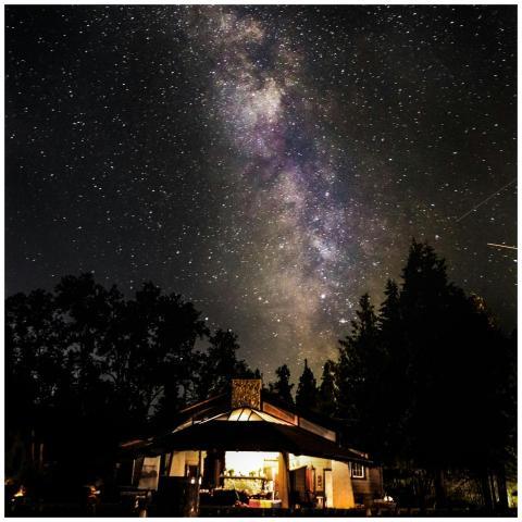 A serene night sky with the Milky Way above a lit