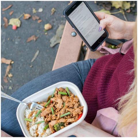 Woman enjoying lunch and checking smartphone on a