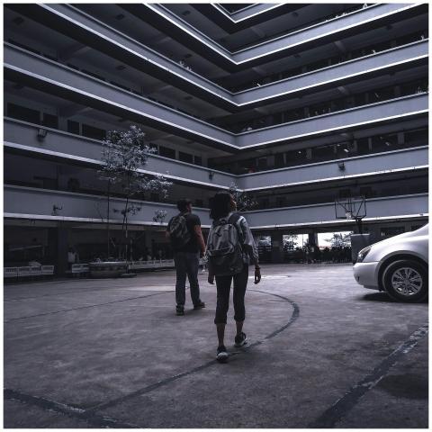 Two backpackers walk through a modern courtyard, h