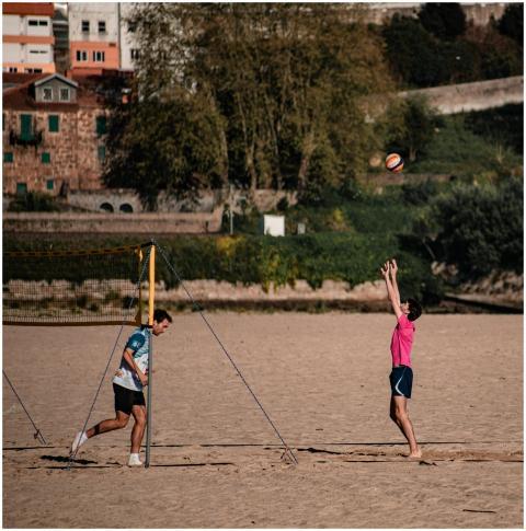 Two men playing beach volleyball on a sunny day, e